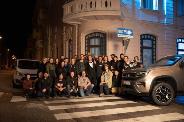 Gruppenbild der gesamten Crew bei der Produktion eines Werbespots vor nächtlicher Straßenszenerie und Fahrzeug
