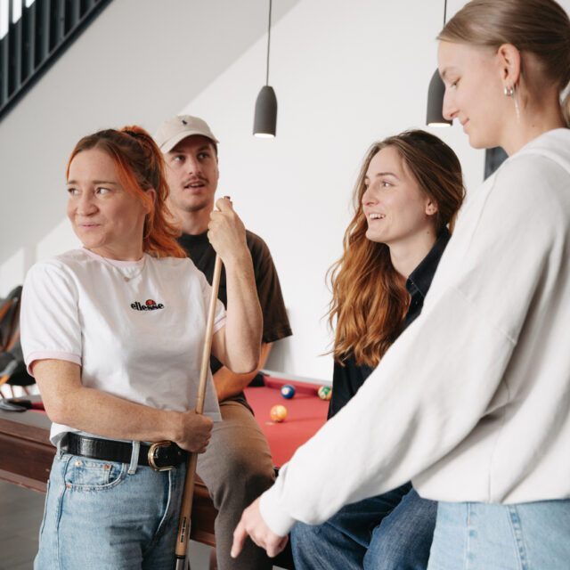Zusammenhalt schafft kreative Energie. Team der Full Service Werbeagentur Wuger in Salzburg beim gemeinsamen Billardspielen im Agenturalltag