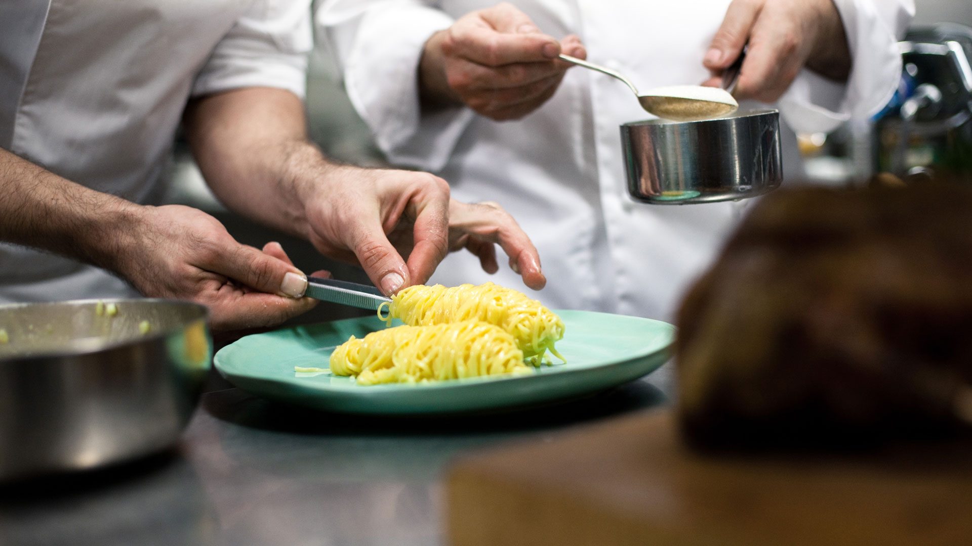 Zwei Köche richten frische Pasta Nester auf einem grünen Teller an als Teil unseres Corporate Design Gastronomie Case für das Restaurant Brunnauer