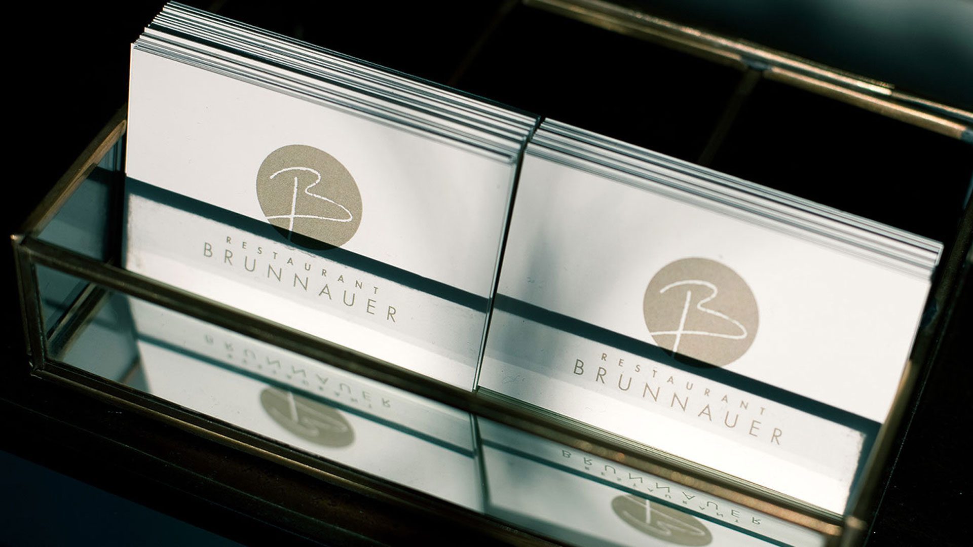 Brunnauer Visitenkarten mit Logo in einer Glasbox, Teil unseres Druckdesigns und Corporate Design Gastronomie Case