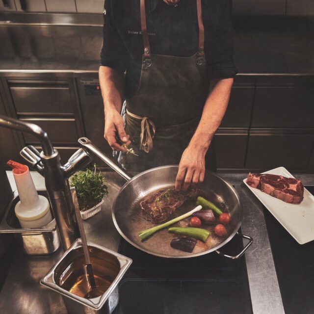 Koch bereitet in Profiküche ein Steak mit Gemüse zu – Food- und Markenfotografie im HOGAST Branding, umgesetzt von WUGER Hospitality.