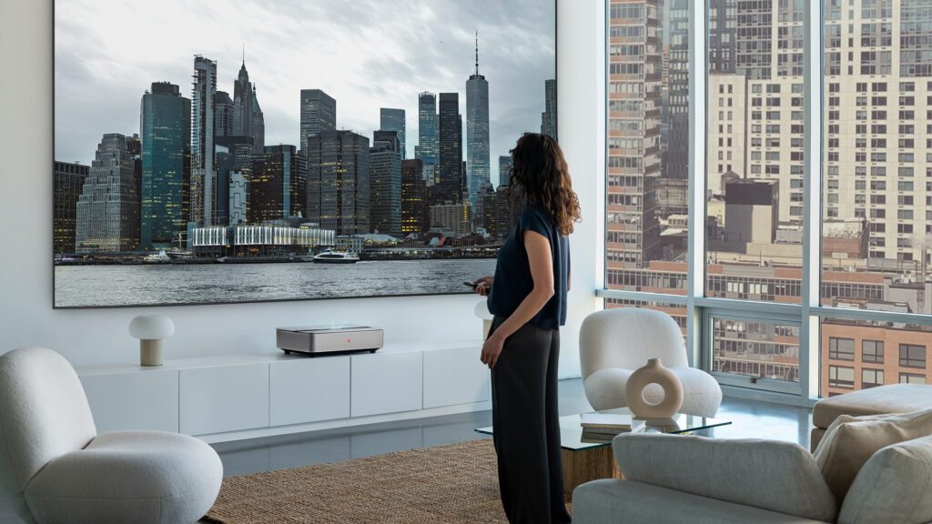 Eine Frau steht in einem modernen Loft und sieht auf eine Projektion der New Yorker Skyline, erzeugt vom Leica Cine 1. Brand Experience WUGER.
