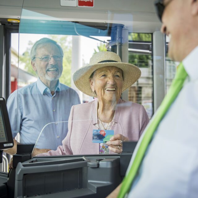 Seniorenpaar zeigt im Bus ein Klimaticket vor und steht stellvertretend für den Social Media Auftritt von Wuger Digital für Salzburg Verkehr