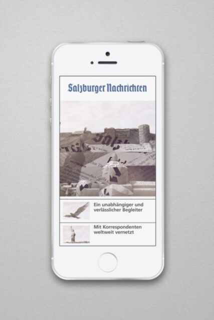 Smartphone mit digitaler Anzeige der Salzburger Nachrichten und Papierwelt-Motiv auf dem Bildschirm