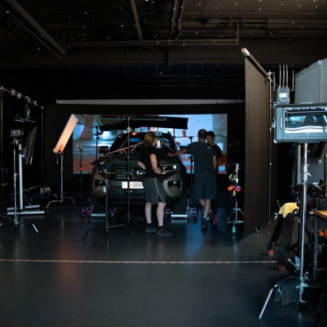 Automotive Werbefilm-Setup im Studio mit präzisem Lichtaufbau und Team am Fahrzeug