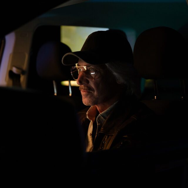 Close-up von Moretti am Filmset, im Auto sitzend, von warmen und kühlen Setlichtern modelliert, als Teil einer nächtlichen Werbespot-Produktion