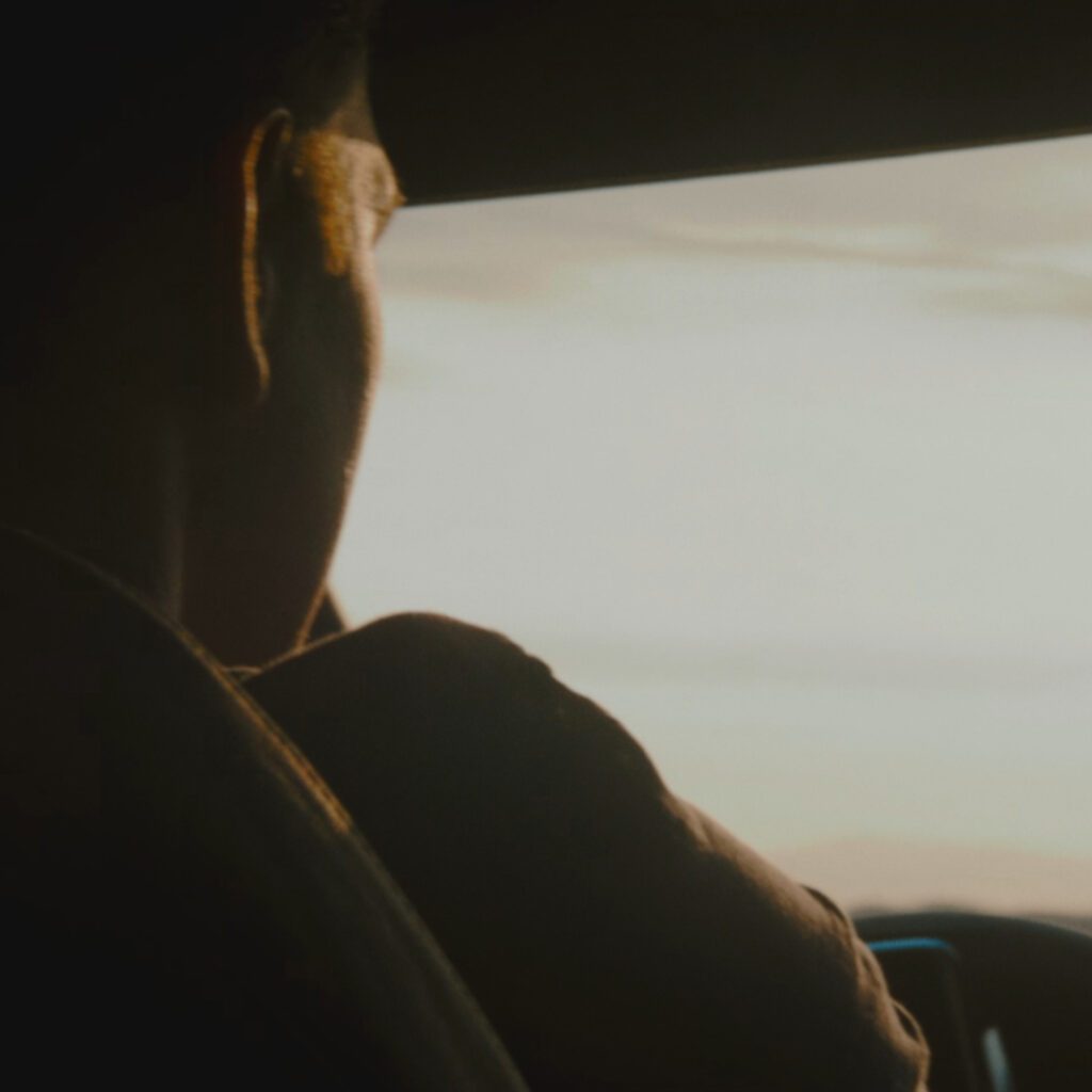 Rückansicht einer Person am Steuer in warmer Lichtstimmung als filmische Szene der TV Spot Produktion gestaltet von Wuger