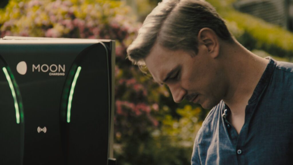 Mann lädt Elektroauto an MOON Ladesäule beim Weingut während der TV Spot Produktion