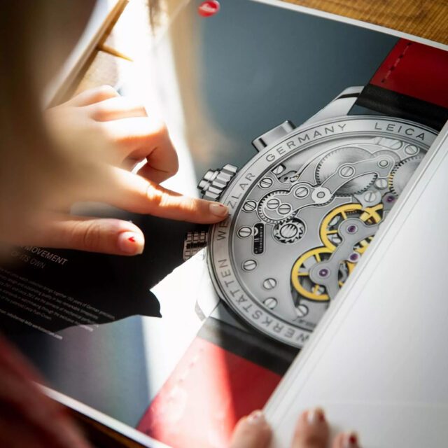 Wuger lässt den Look deiner Marke in den größten Inszenierungen und kleinsten Details strahlen. Person blättert durch von Wuger designtes Magazin, das die Markenästhetik hervorhebnt