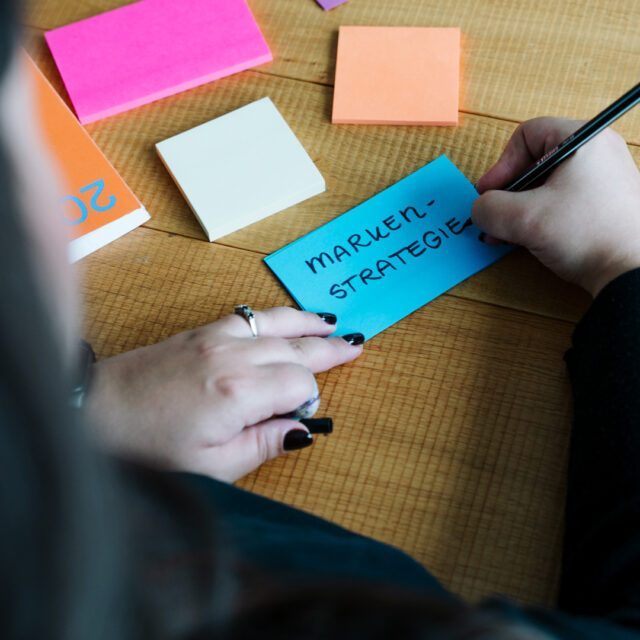 Wuger denkt Marken mit echter Strategie Wuger Mitarbeiterin schreibt Post-Its zur Markenstrategie in einem Planungsmeeting