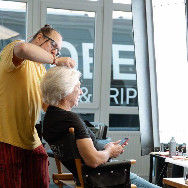 Stylist richtet Haare einer Person am Set für ein Fotoshooting