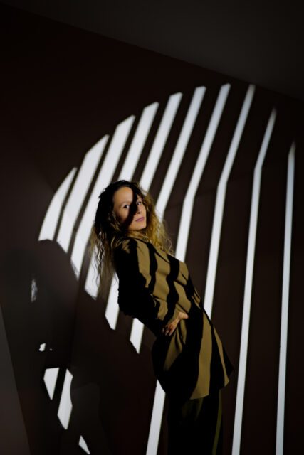 Person in einem dunklen Setting mit markanten, vertikalen Lichtstreifen fotografiert von Wuger für ein stilvolles, grafisch geprägtes Eventmotiv