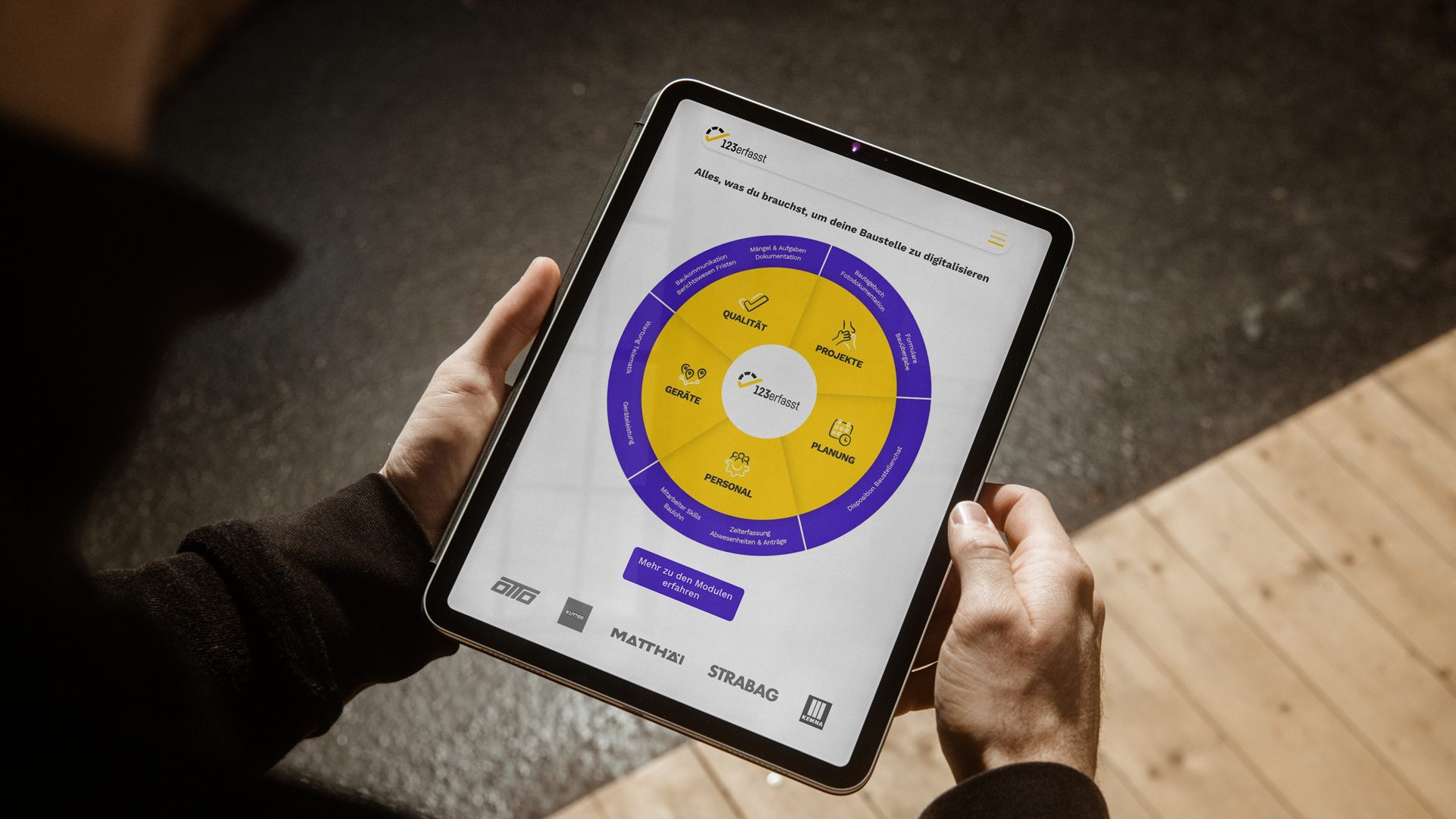 Person hält ein Tablet, das die digitale Baumanagement-Software zeigt, gestaltet von Wuger im Zuge der Digitalkampagne