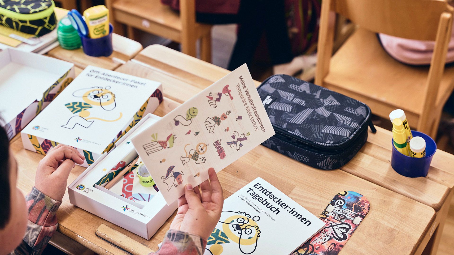 Eigenständiges Entdecken der Materialien vertieft Inhalte und stärkt spielerisches Lernen. Foto zeigt ein Schulkind mit Stickerbogen und Entdeckerbox, die Wuger im Event Marketing für Mobilität entwickelt hat