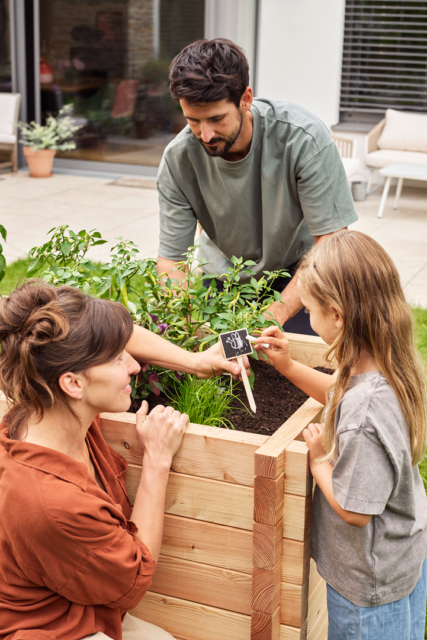 Familie am Hochbeet auf der Terrasse, aufgenommen als emotionales Lifestyle-Imageshooting für authentische Markenkommunikation
