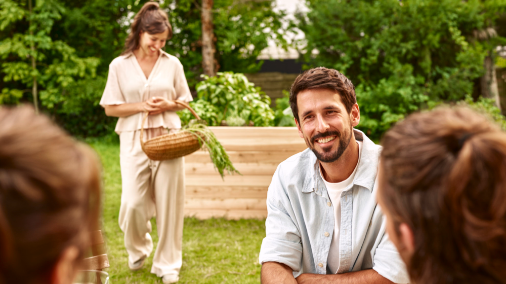 Lachender Mann und Frau mit Erntekorb vor Hochbeet für Lifestyle-Imageshooting für authentisches Rebranding