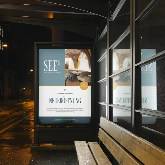 Während die Straße im Regen glänzt, verspricht das Leuchtplakat schon, was ab Juni aufgetischt wird. Nächtliches City-Light-Poster als Kampagne und Corporate Design von WUGER, das die Neueröffnung an der Haltestelle ankündigt
