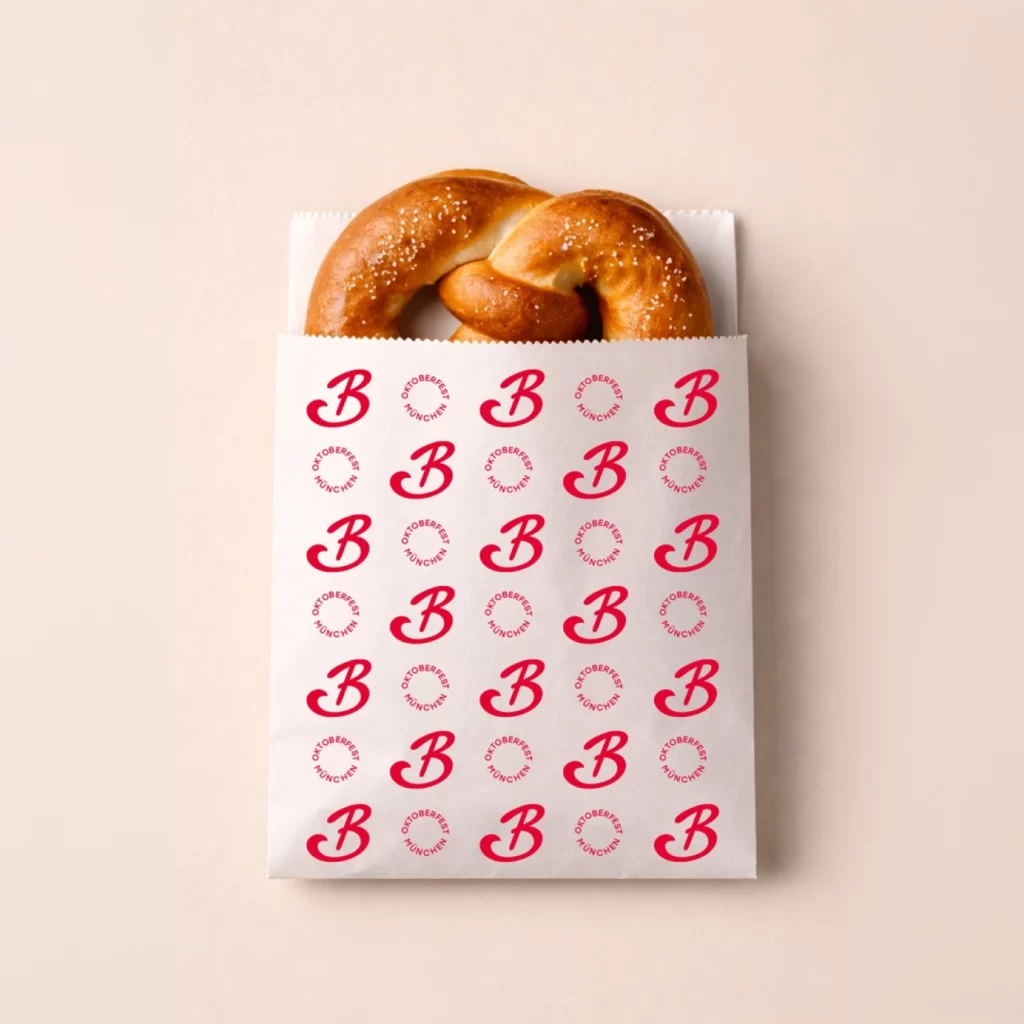Wer die Tüte trägt, trägt die Marke mit durch die Wiesn. Gebrandete Papiertüte mit Markenmuster und Brezel als Verpackungsdesign
