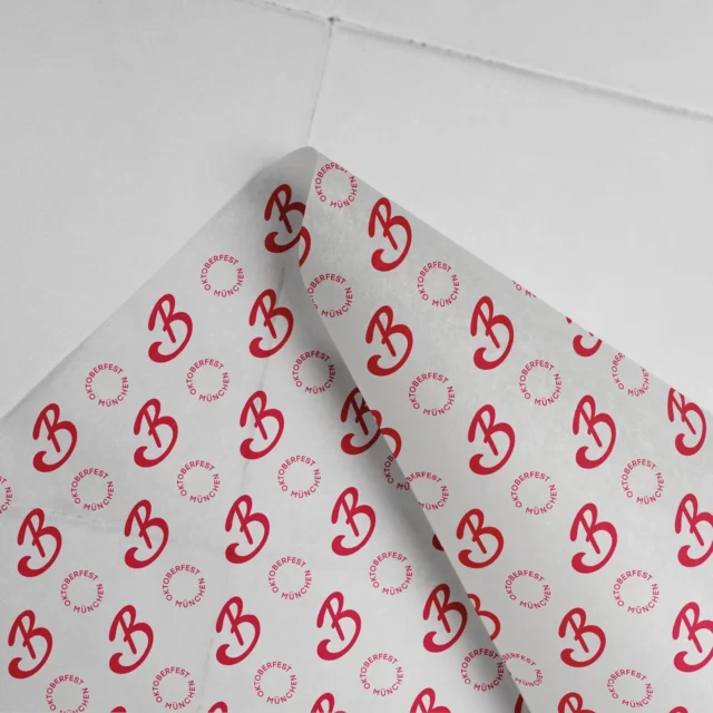 Selbst das Einwickelpapier arbeitet für die Marke, noch bevor der Krapfen gegessen ist. Seidenpapier mit Markensignet als gebrandetes Verpackungsmaterial im Gastronomie-Rebranding für Bodos
